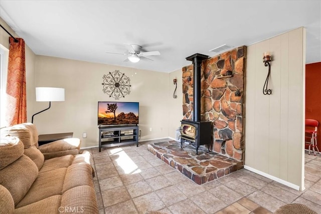 tiled living room featuring ceiling fan and a wood stove