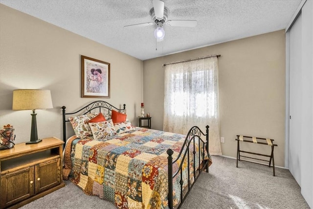 carpeted bedroom featuring ceiling fan and a textured ceiling