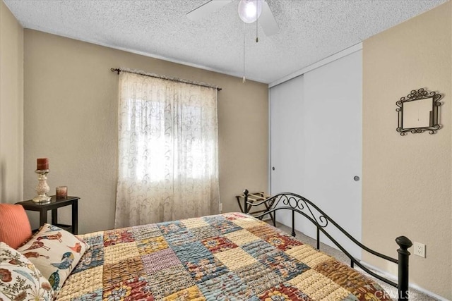 bedroom featuring ceiling fan, carpet floors, a closet, and a textured ceiling