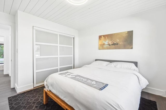 bedroom featuring dark wood-type flooring, wooden ceiling, and a closet