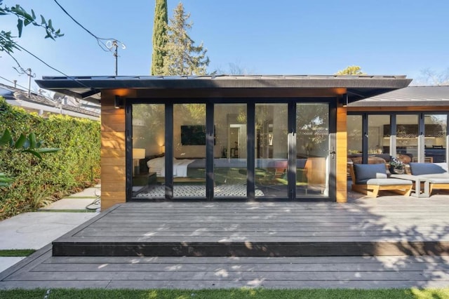 rear view of property featuring a sunroom and a deck