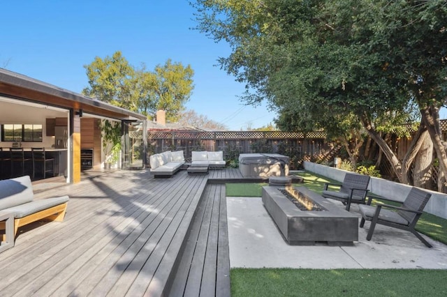 deck featuring a hot tub and an outdoor living space with a fire pit