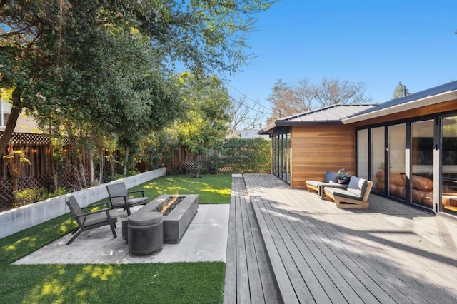 wooden deck featuring a patio area, a fire pit, and a lawn