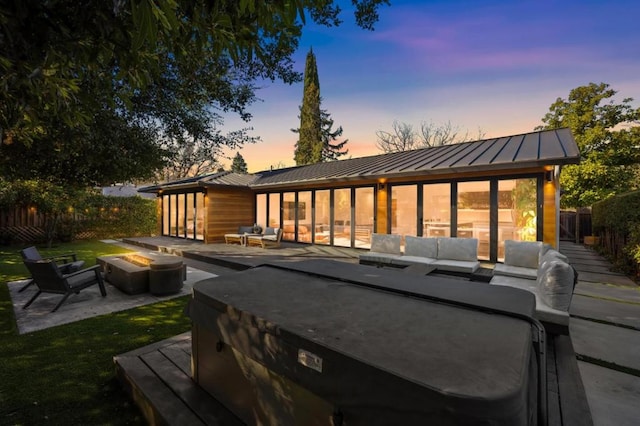 deck at dusk featuring an outdoor living space with a fire pit and a patio