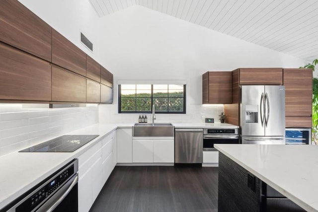 kitchen with sink, white cabinets, decorative backsplash, stainless steel appliances, and dark wood-type flooring