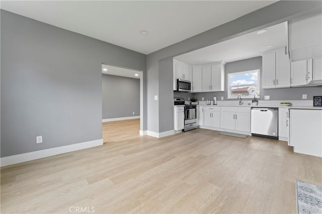 kitchen featuring stainless steel appliances, sink, light hardwood / wood-style floors, and white cabinets