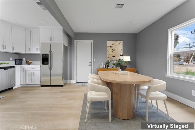 dining area with a wealth of natural light and light wood-type flooring