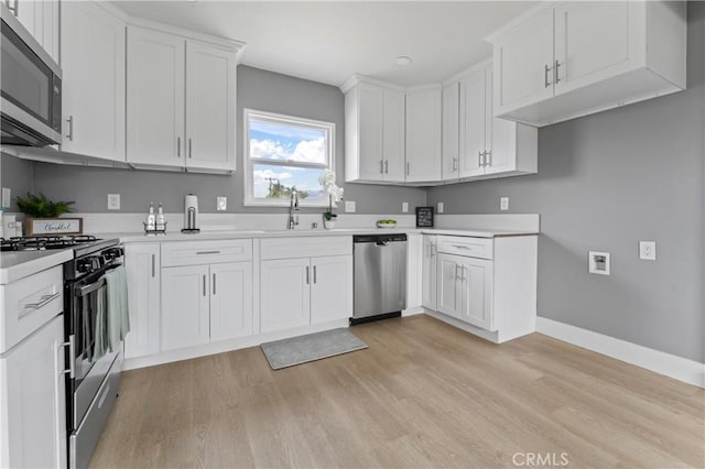 kitchen featuring stainless steel appliances, sink, light hardwood / wood-style floors, and white cabinets