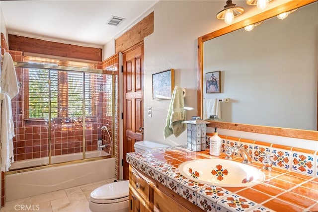 full bathroom featuring vanity, tile patterned flooring, bath / shower combo with glass door, and toilet