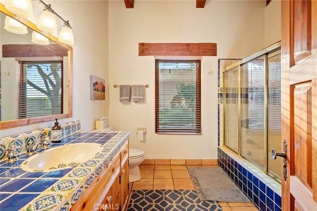 full bathroom with tile patterned floors, toilet, combined bath / shower with glass door, and vanity