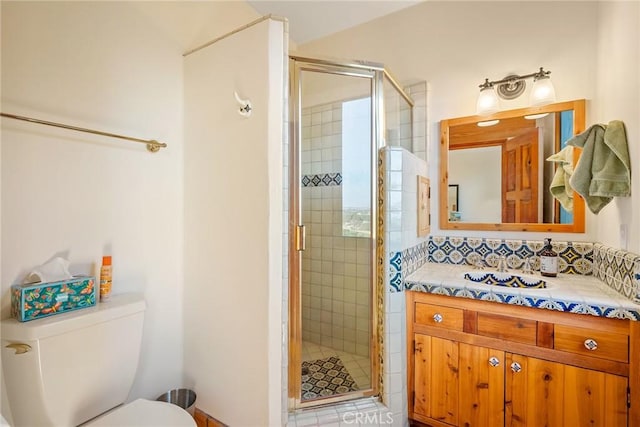 bathroom featuring vanity, backsplash, toilet, and walk in shower