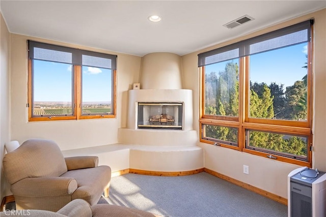 living area featuring a healthy amount of sunlight, carpet, and a large fireplace