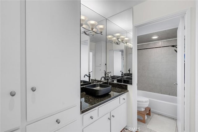 full bathroom featuring tiled shower / bath, vanity, a notable chandelier, toilet, and tile patterned floors