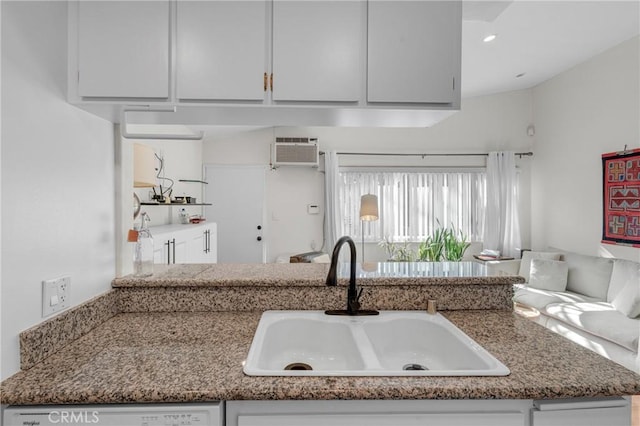 kitchen featuring sink, white dishwasher, white cabinets, and a wall unit AC