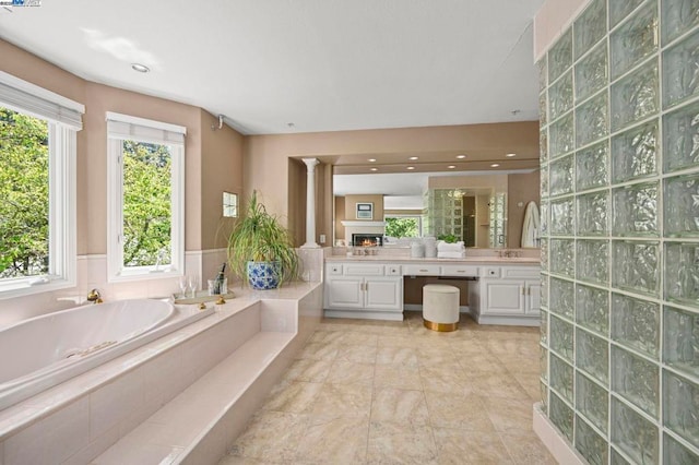 bathroom with vanity, tiled bath, and decorative columns