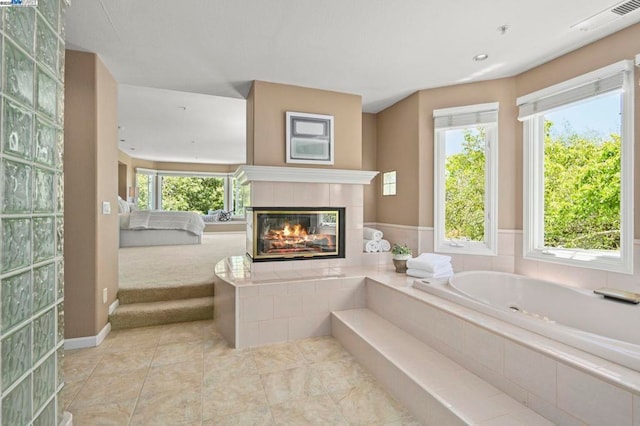 bathroom featuring a relaxing tiled tub and a fireplace