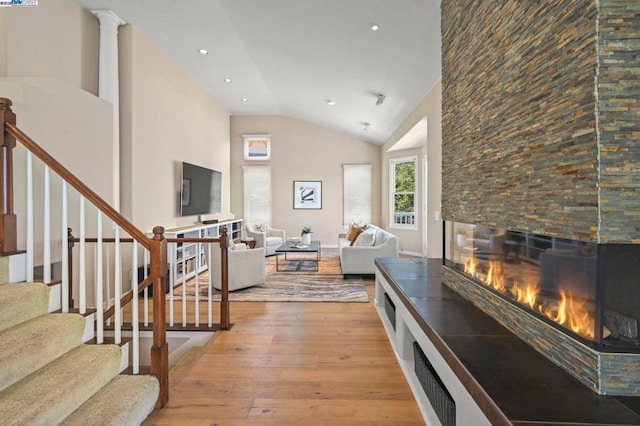 living room featuring high vaulted ceiling, light hardwood / wood-style flooring, and ornate columns