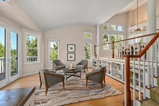 interior space featuring an inviting chandelier, light hardwood / wood-style flooring, high vaulted ceiling, and plenty of natural light