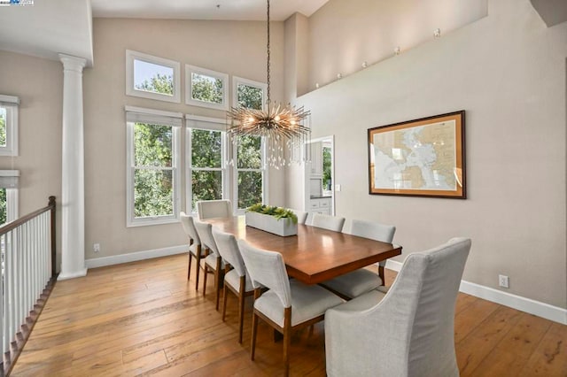 dining area with an inviting chandelier, high vaulted ceiling, decorative columns, and light wood-type flooring