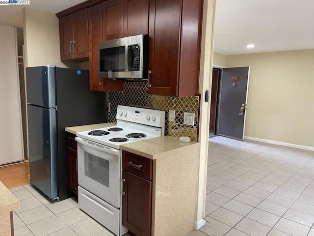 kitchen with tasteful backsplash, white electric stove, black fridge, and light tile patterned floors