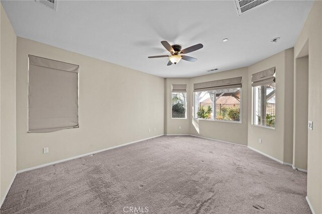 spare room with carpet floors, ceiling fan, visible vents, and baseboards