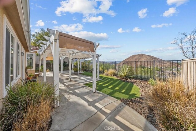 view of patio featuring fence, a mountain view, and a pergola