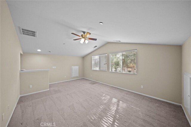 spare room featuring lofted ceiling, carpet floors, baseboards, and visible vents