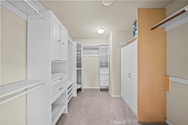 walk in closet featuring light carpet