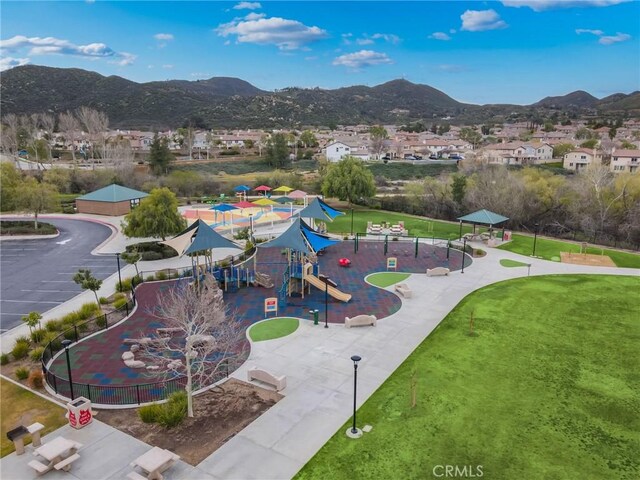 view of community featuring playground community, a lawn, a residential view, and a mountain view