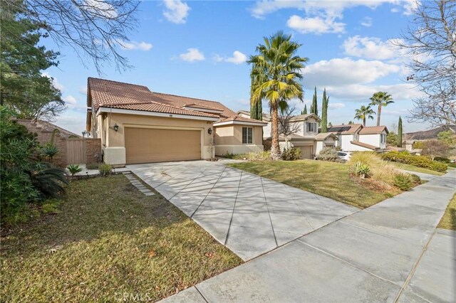 mediterranean / spanish-style home with stucco siding, concrete driveway, a garage, a tiled roof, and a front lawn