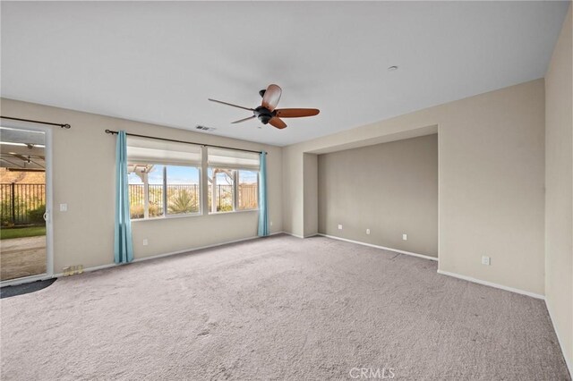 empty room with carpet floors, baseboards, visible vents, and a ceiling fan