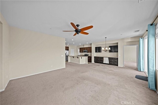 unfurnished living room with light carpet, ceiling fan with notable chandelier, visible vents, and baseboards