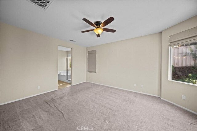 carpeted spare room featuring baseboards, visible vents, and a ceiling fan