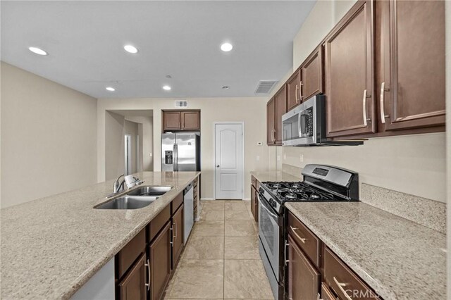 kitchen featuring light stone counters, stainless steel appliances, recessed lighting, visible vents, and a sink