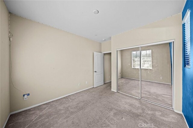 unfurnished bedroom with carpet floors, baseboards, and a closet