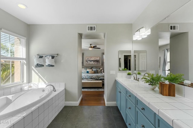 bathroom with a relaxing tiled tub, ceiling fan, tile patterned floors, and vanity