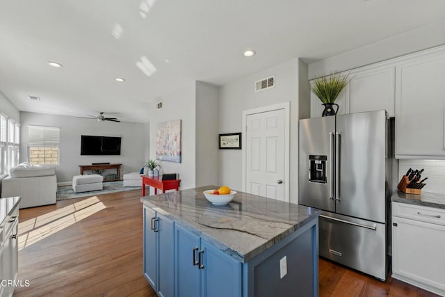 kitchen with high quality fridge, white cabinets, a center island, light stone countertops, and blue cabinetry