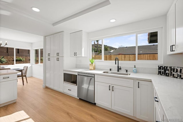 kitchen with black microwave, sink, stainless steel dishwasher, and white cabinets