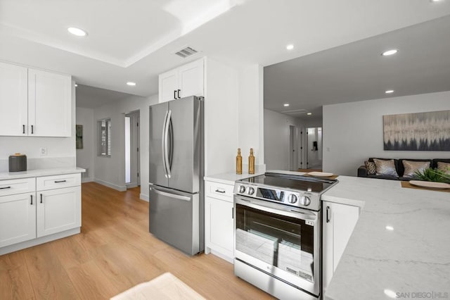 kitchen featuring light stone counters, light wood-type flooring, white cabinets, and appliances with stainless steel finishes