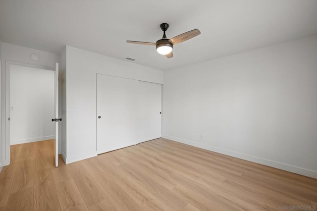 unfurnished bedroom featuring ceiling fan, light wood-type flooring, and a closet