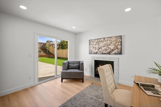 office area with a tiled fireplace and light hardwood / wood-style flooring