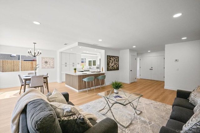 living room with an inviting chandelier and light hardwood / wood-style floors