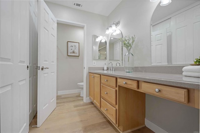 bathroom with wood-type flooring, vanity, and toilet