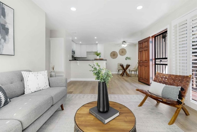 living room with light hardwood / wood-style flooring and ceiling fan