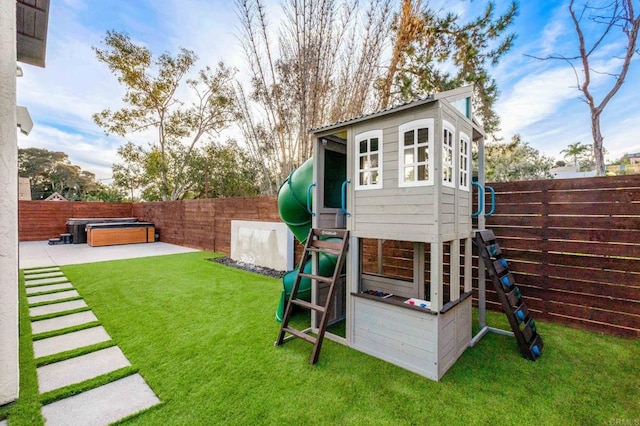 view of jungle gym with a hot tub, a patio area, and a lawn