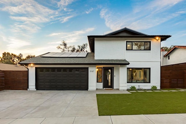 view of front of house with a garage, a front lawn, and solar panels