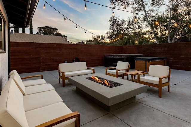 patio terrace at dusk with a hot tub and an outdoor living space with a fire pit