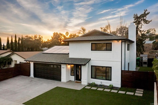 view of front facade featuring a garage, a lawn, and solar panels