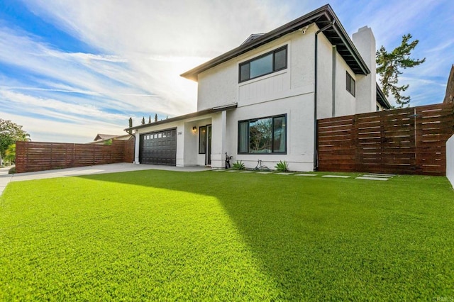 rear view of property with a garage and a lawn