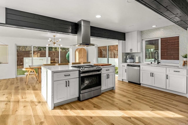 kitchen with a healthy amount of sunlight, island exhaust hood, appliances with stainless steel finishes, and white cabinets